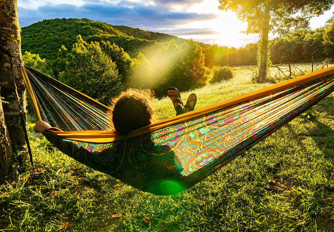 A woman sits in an ENO Mantra hammock as the sun sets over the mountains ahead. 