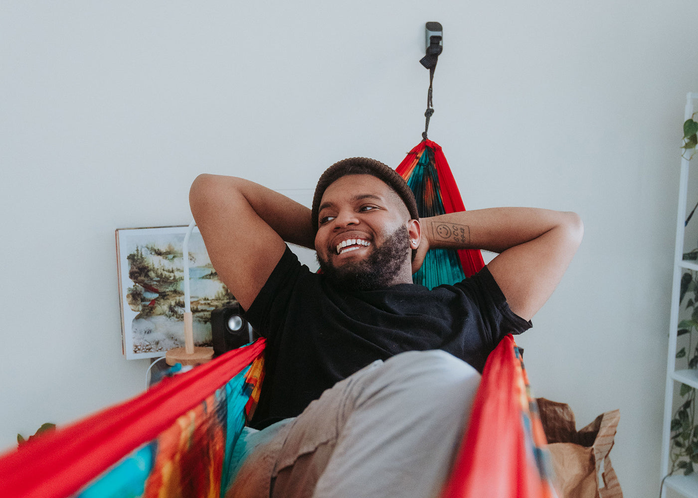 A man uses a deluxe indoor hammock hanging kit while in a room.
