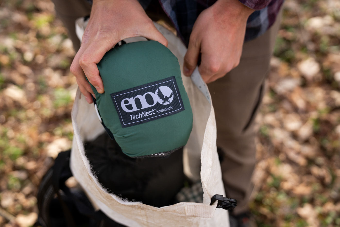 A man pulls an ENO TechNest Hammock out of his backpack.