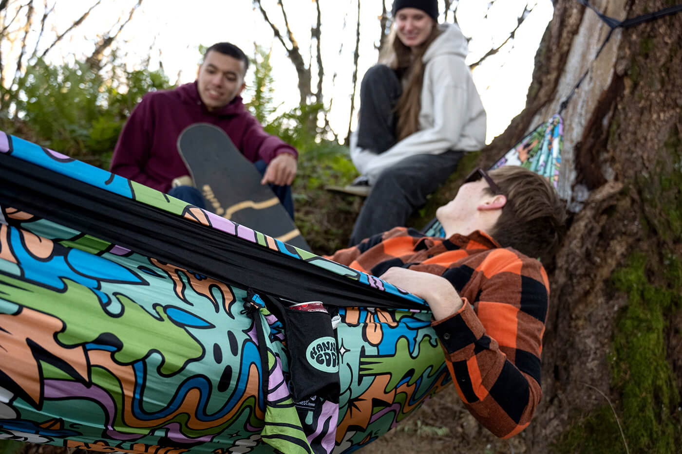 A group of friends talk and hangout in the Hannah Eddy Nature Talk DoubleNest Print Hammock
