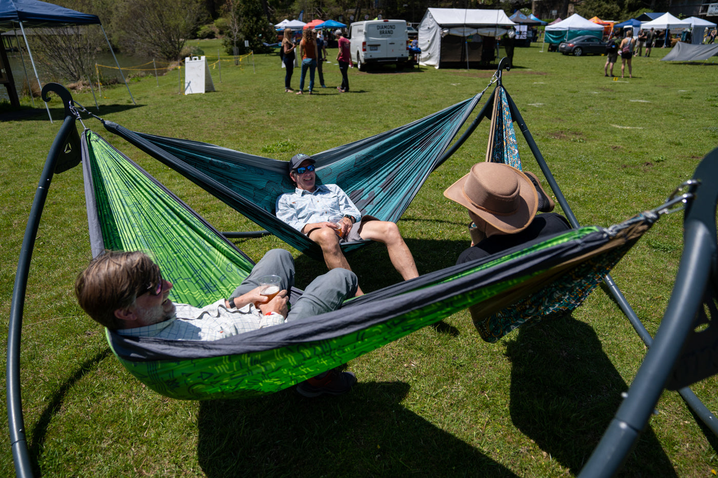 Three people relax and chat in hammocks in a three-person hammock stand, the ENOpod. 