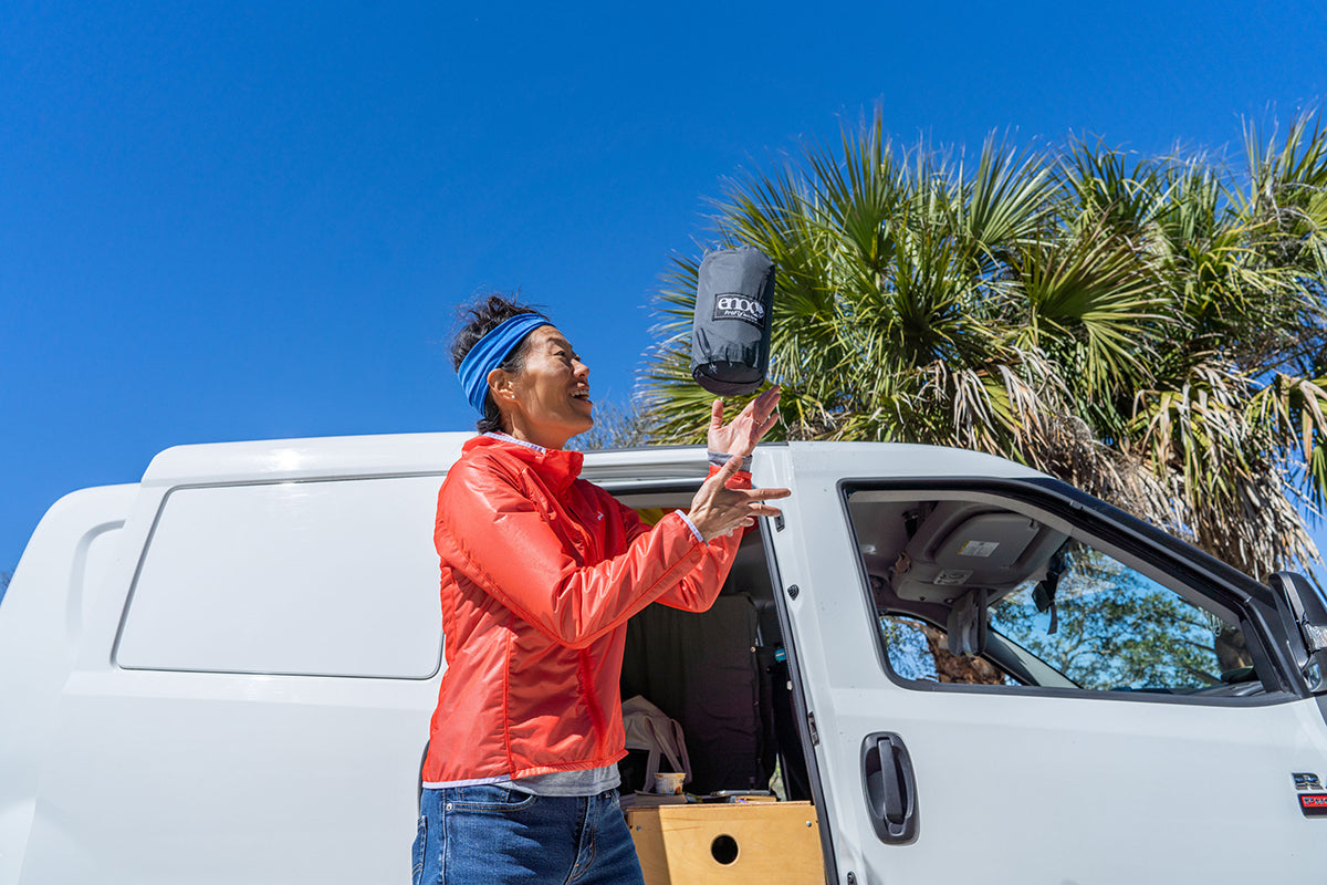 A woman throws the ProFly stuff sack into the air outside of their camper van.