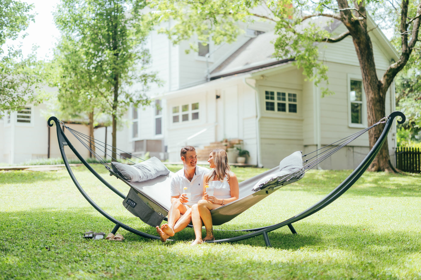 A couple sits in a SuperNest SL Hammock in the SoloPod XL Hammock Stand.