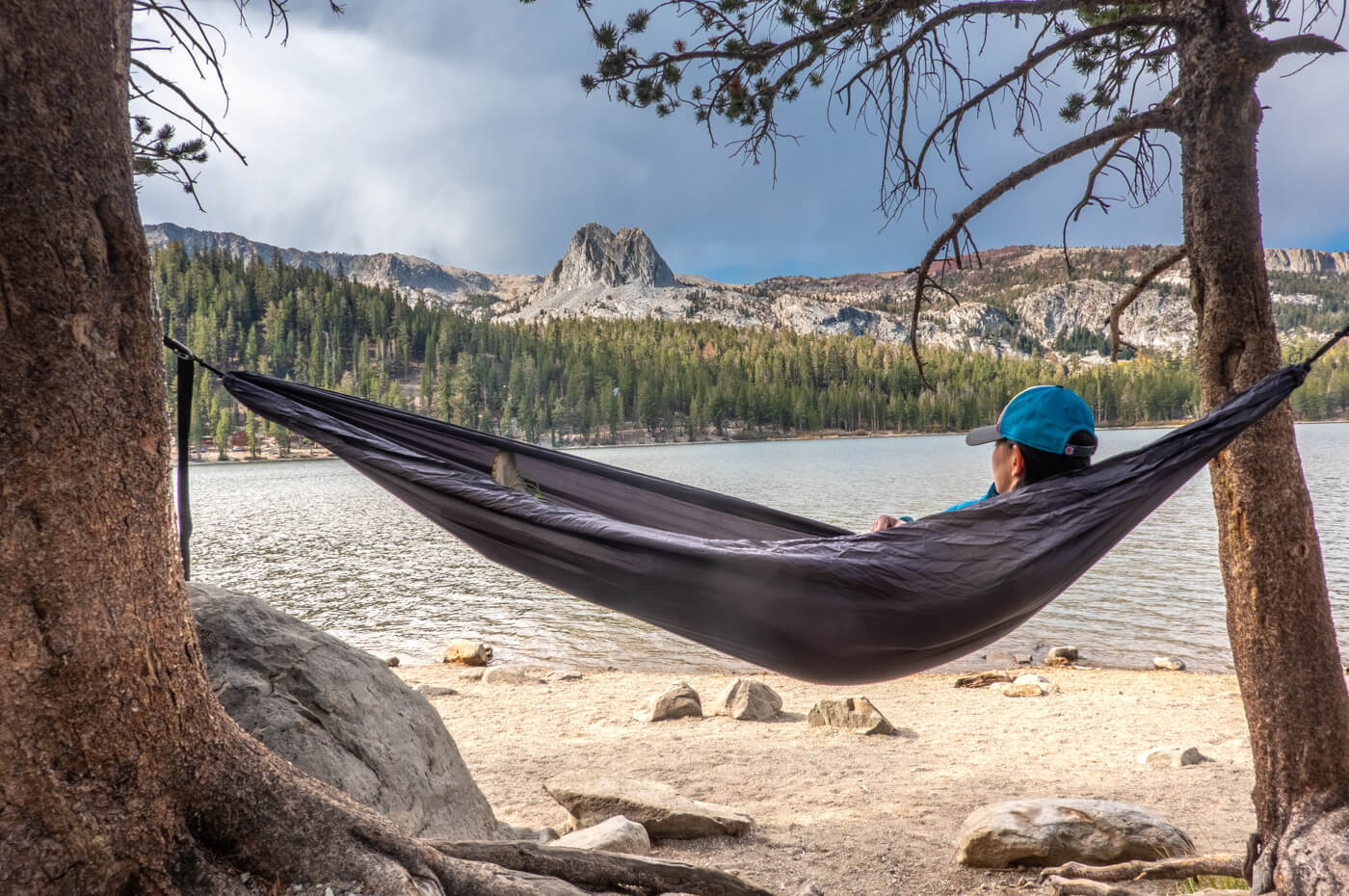 A woman sits in the TravelNest and looks away at the mountains in the distance