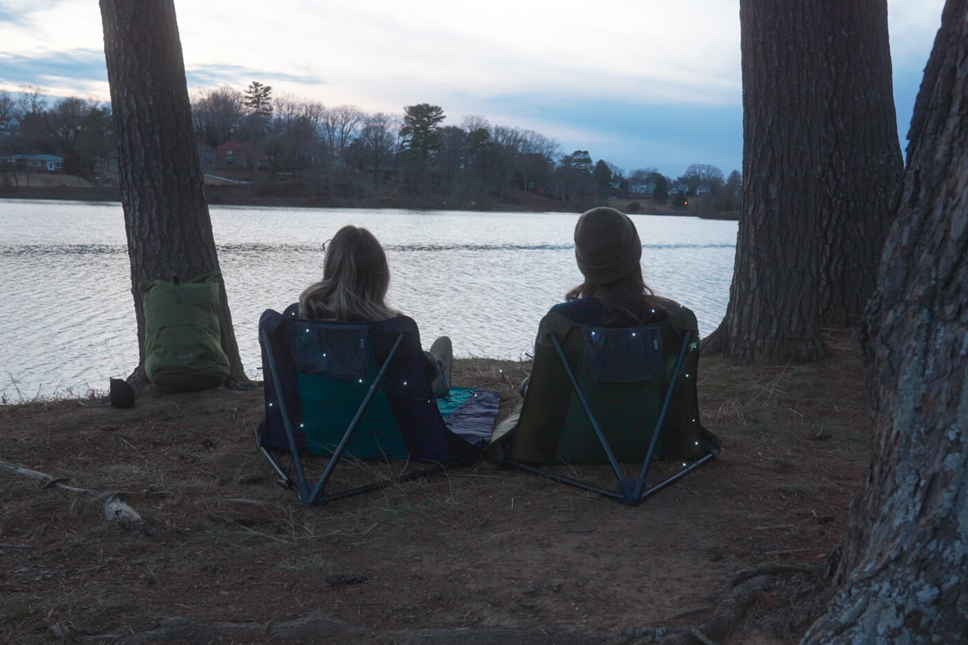 Two people sit in ENO Lounger GL Chairs in front of a lake and watch the sunset. 