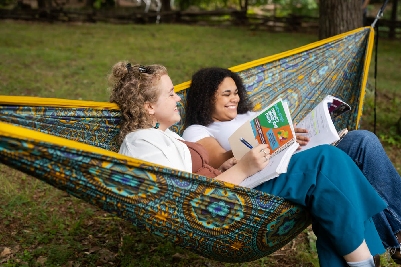 Two college aged girls share a Mantra DoubleNest Print Hammock while studying