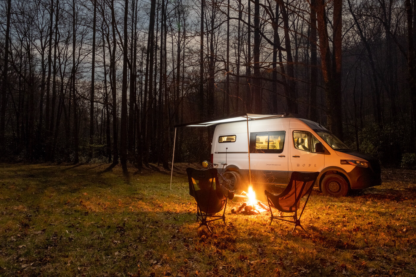 Two Lounger DL Chairs sit by a campfire with a van nearby. 