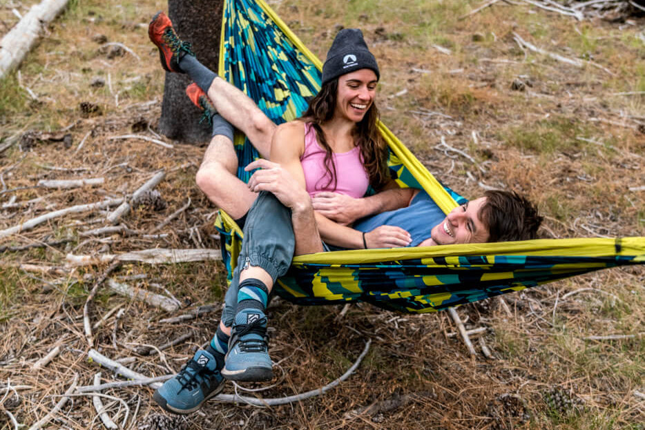 Two people share a Boulder DoubleNest hammock print in between climbing sessions. 