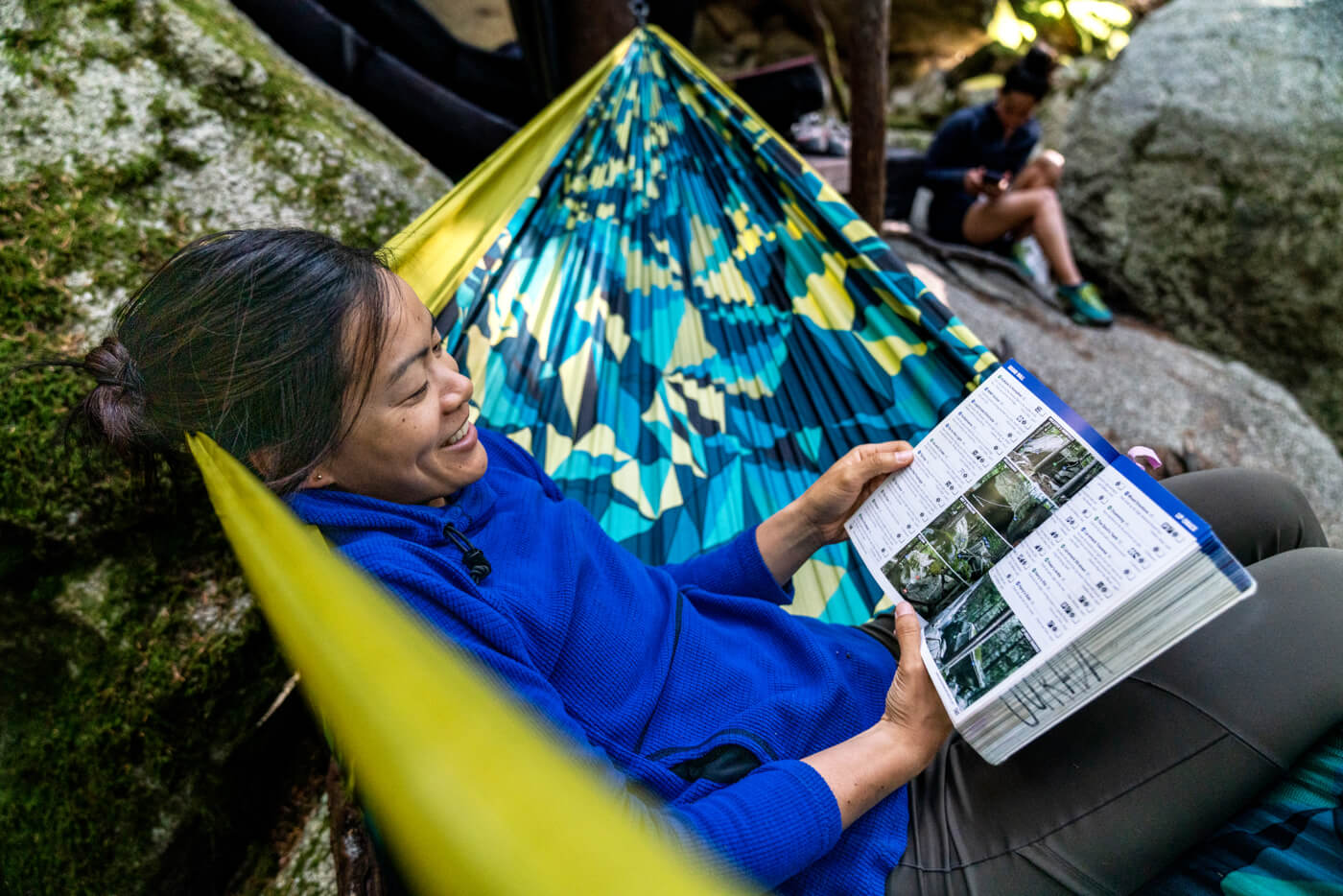 A woman reads a climbing book while hanging out in a Boulder DoubleNest Hammock Print