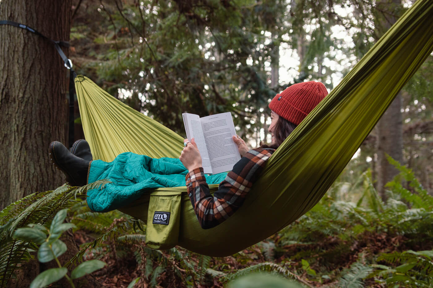 A woman reads while laying in her ENO TravelNest Hammock and Straps Combo