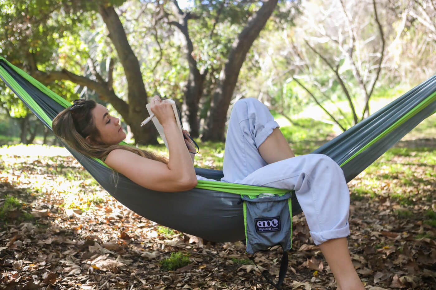 A girl journals while resting in an ENO SingleNest Hammock