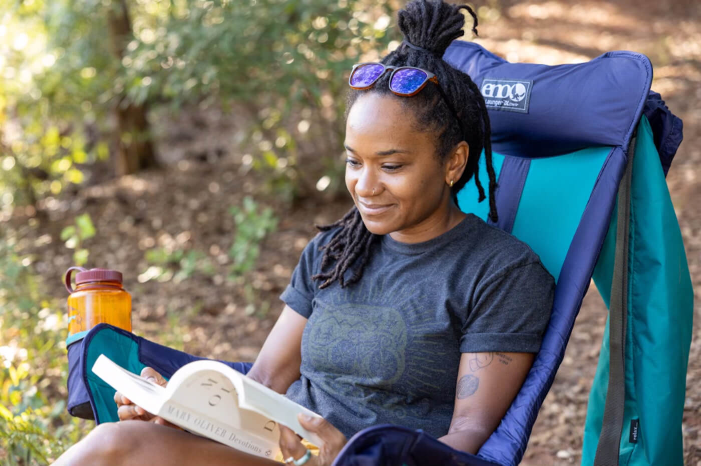 A woman sits in her Lounger DL Chair while reading a book outside.