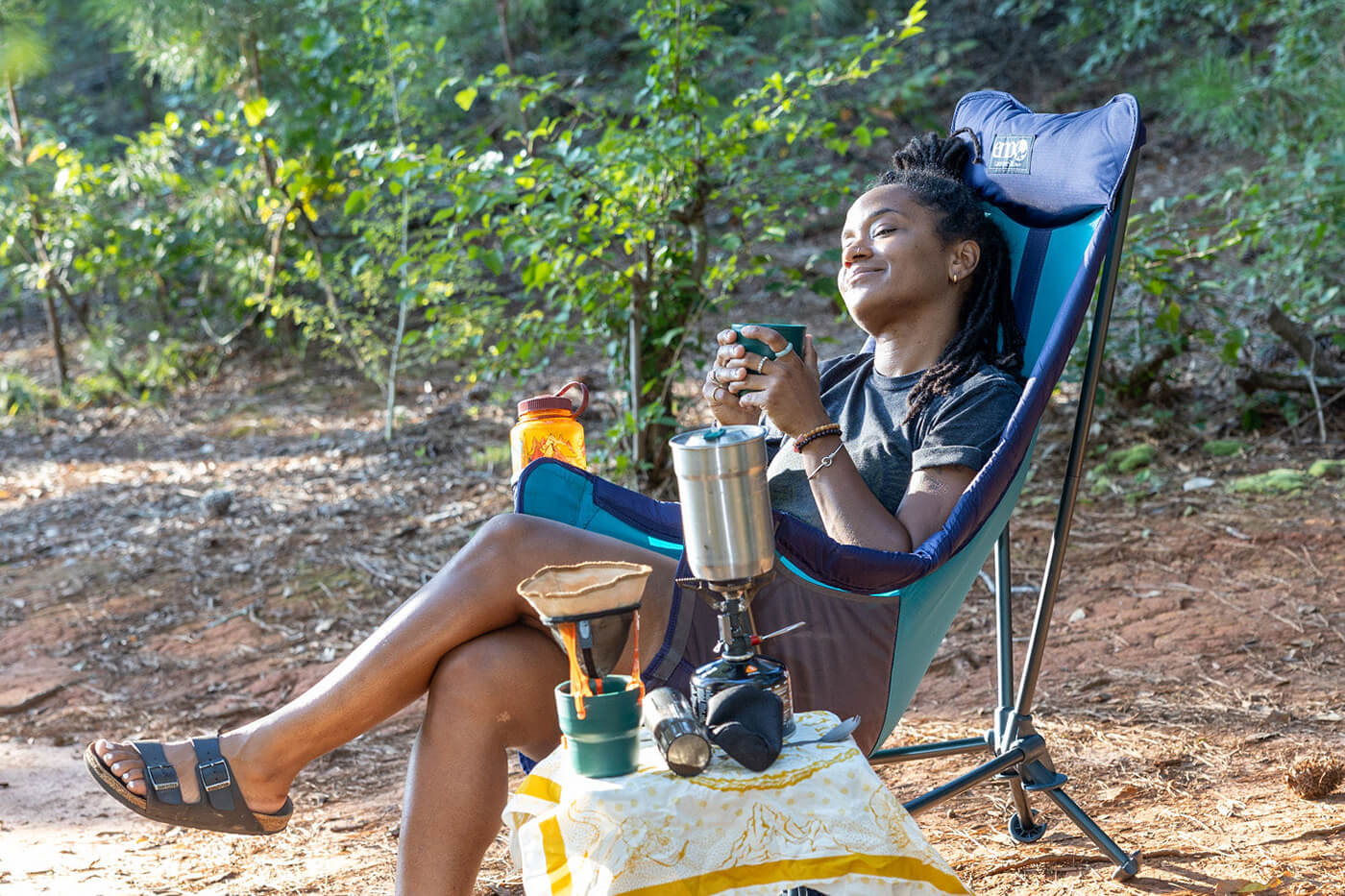 A woman sits in her ENO Lounger DL Chair while enjoying a cup of coffee outside
