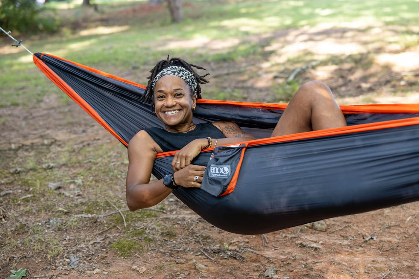 A woman lays in her ENO SuperSub Ultralight Hammock while in the park