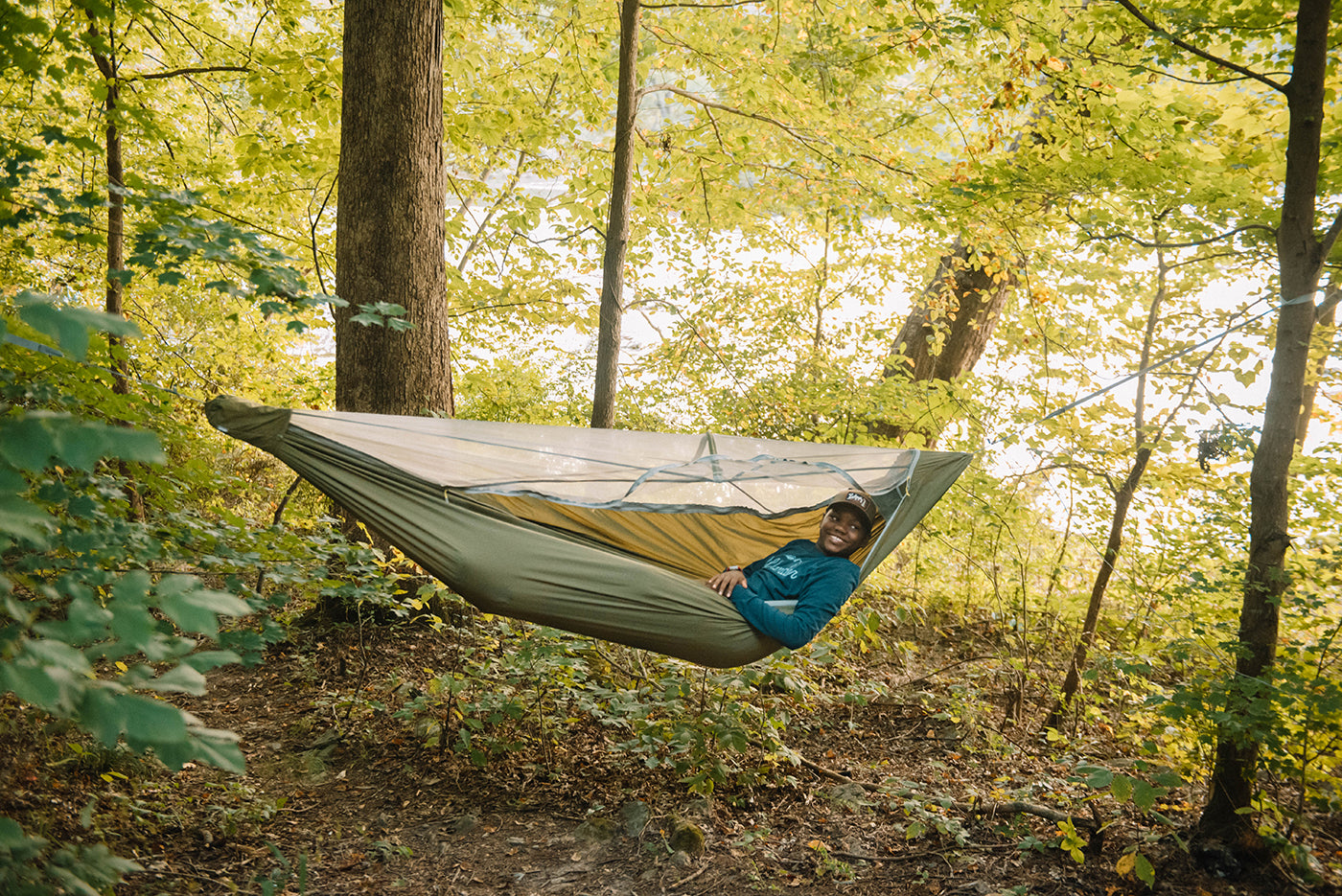A boy lays in a JungleNest Hammock while in the forest.