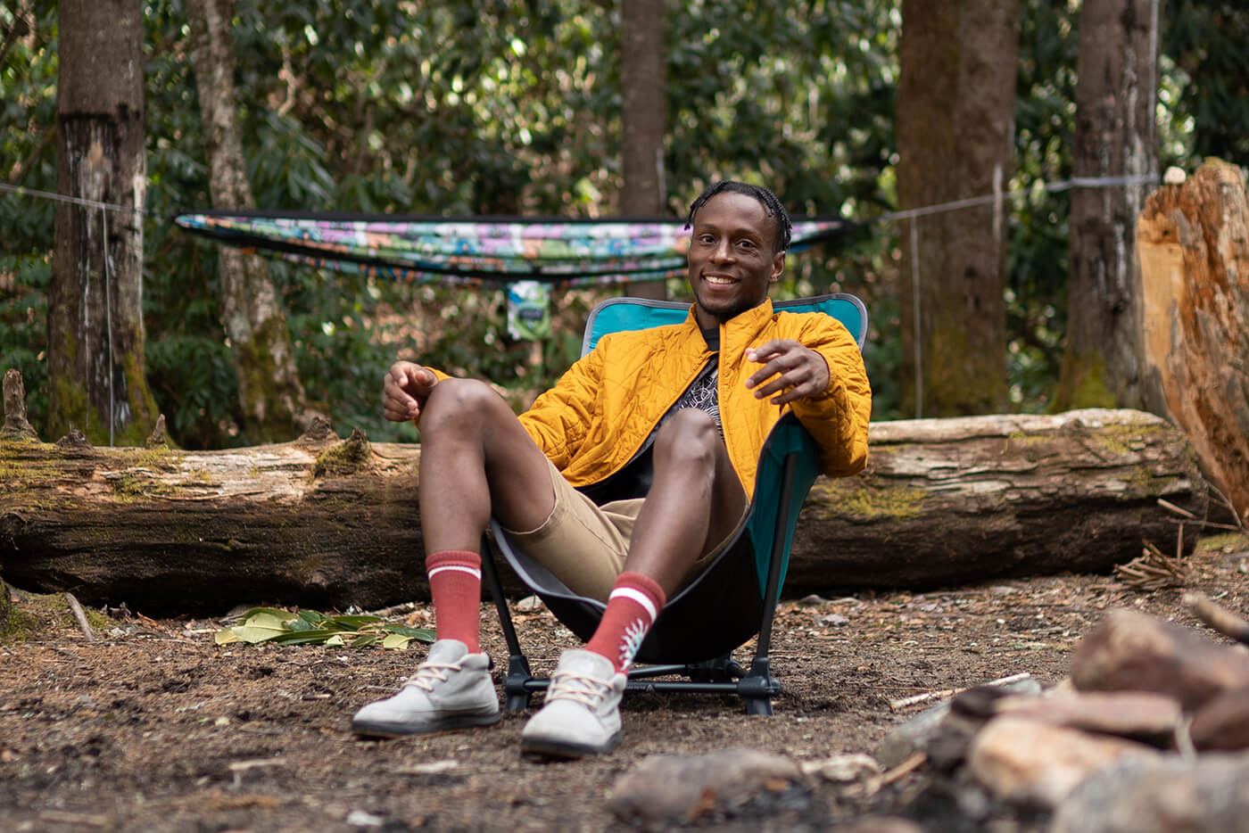 A man sits in an ENO Lounger SL camp chair in the woods. 