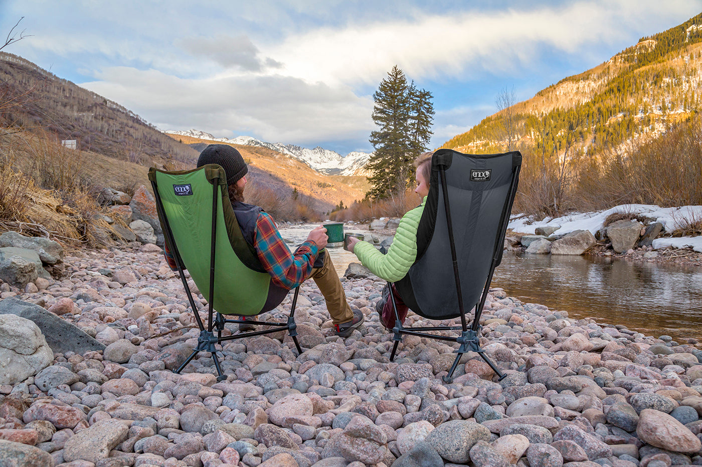 Two people cheers their coffee mugs while facing mountain views in Lounger DL Chairs.