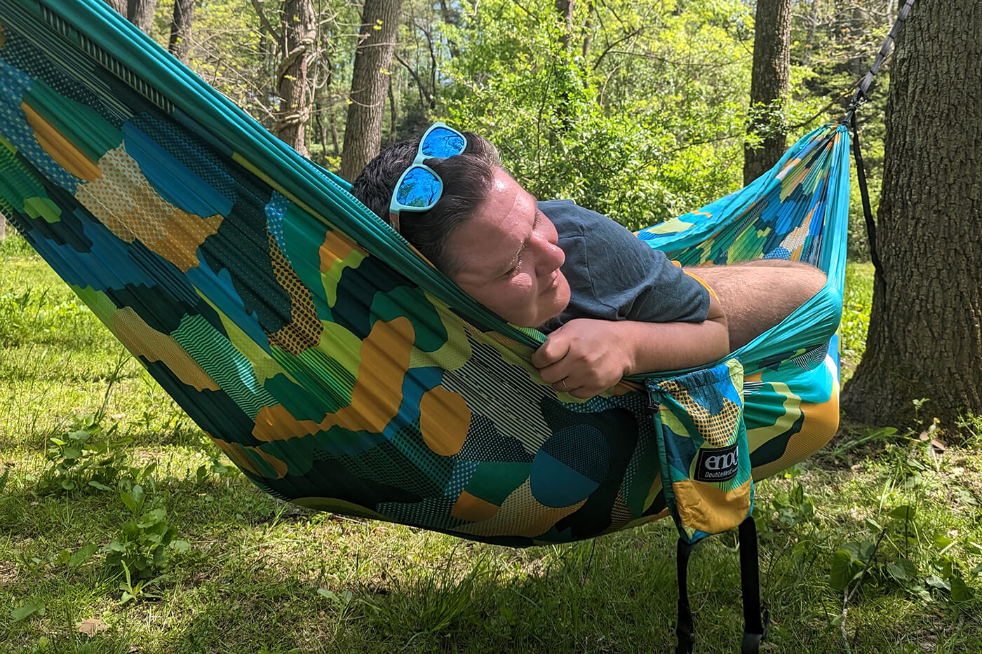 A trans man relaxes in an ENO DoubleNest Print Hammock. 