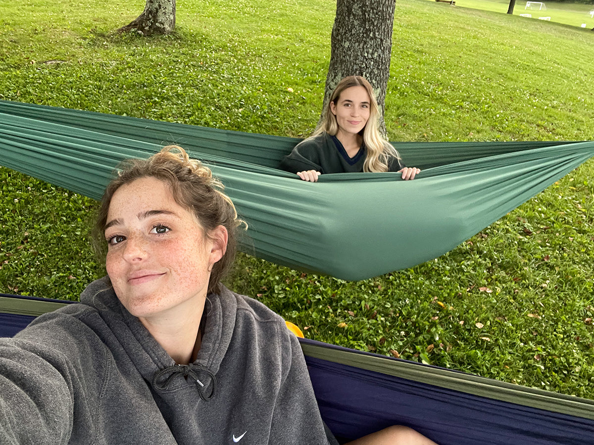 A couple takes a selfie while hammocking together in the park.