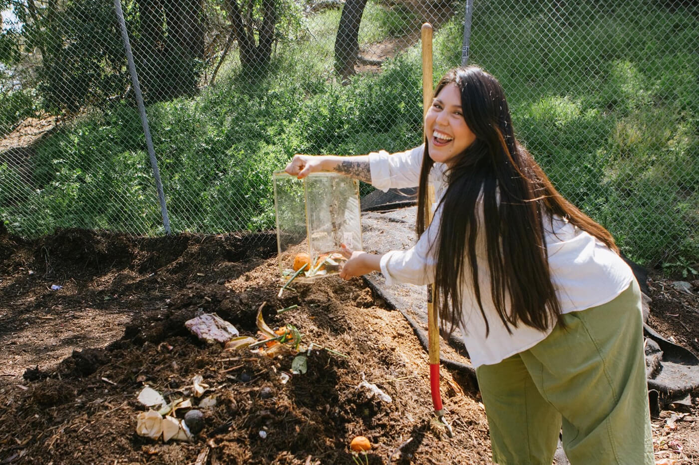 Cindy dumping compost into a pile in her backyard. 
