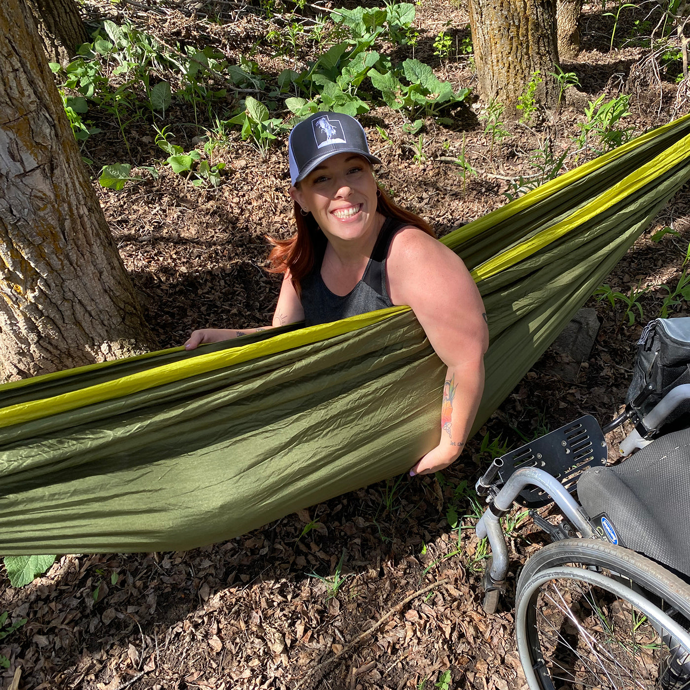 Kerri sits in a green ENO DoubleNest Hammock and smiles at the camera