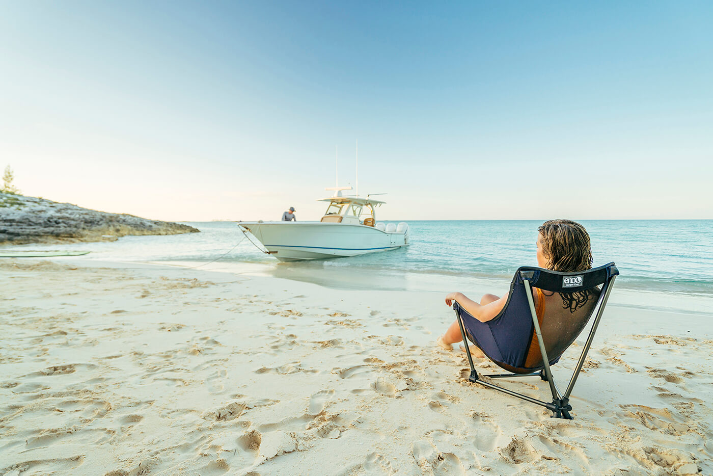 A woman sits in a Lounger SL Chair on the beach