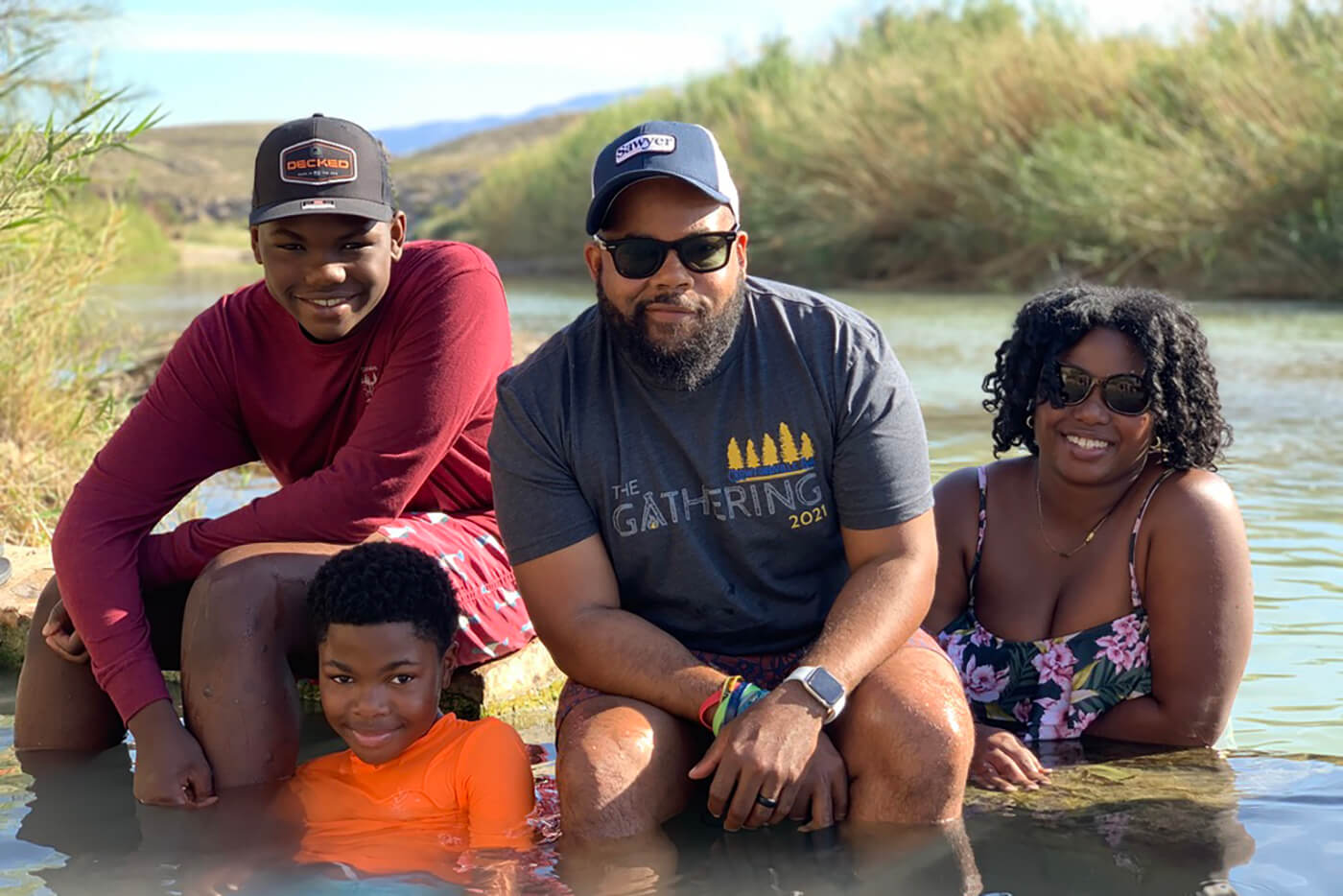 A family poses for a portrait while sitting in a river. 