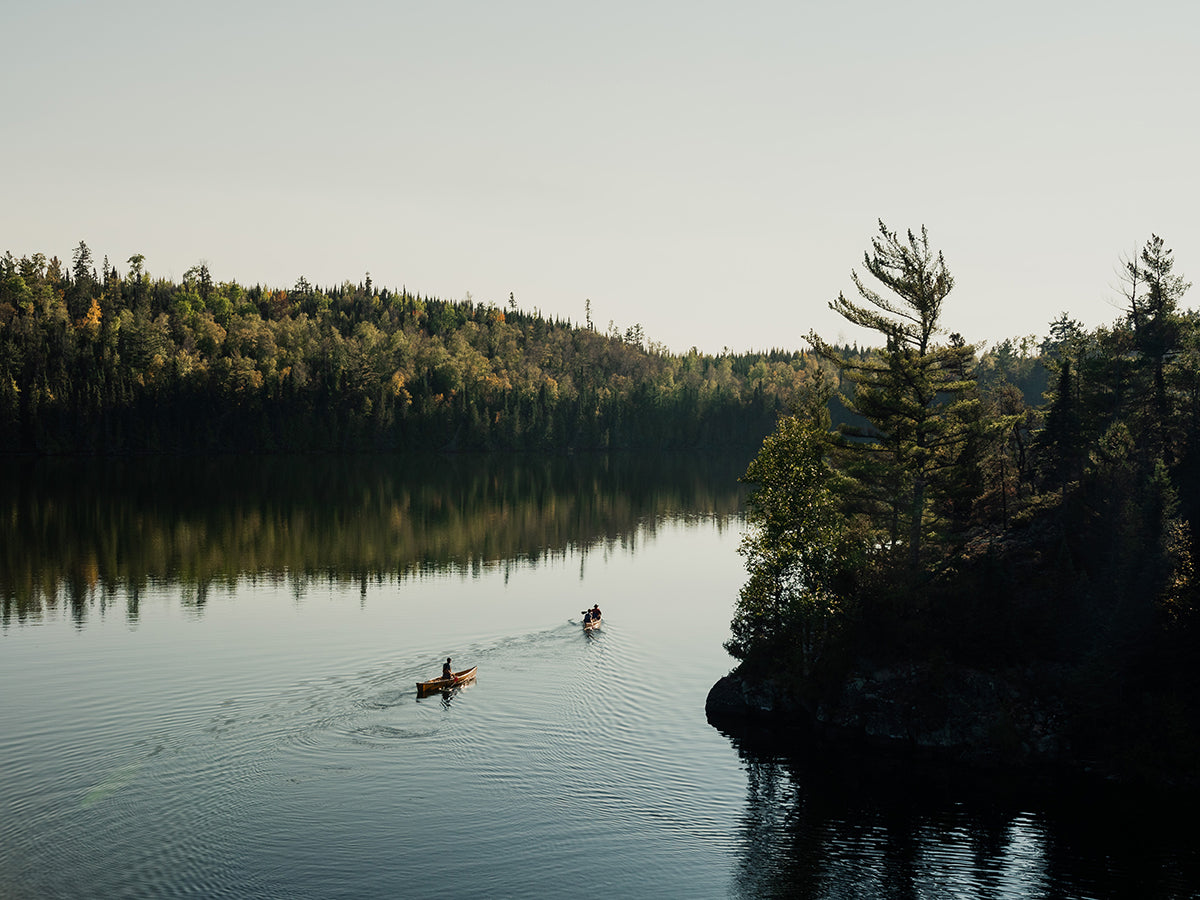 Two canoes paddle off into the distance while on in the Boundary Waters Canoe Wilderness in Minnesota