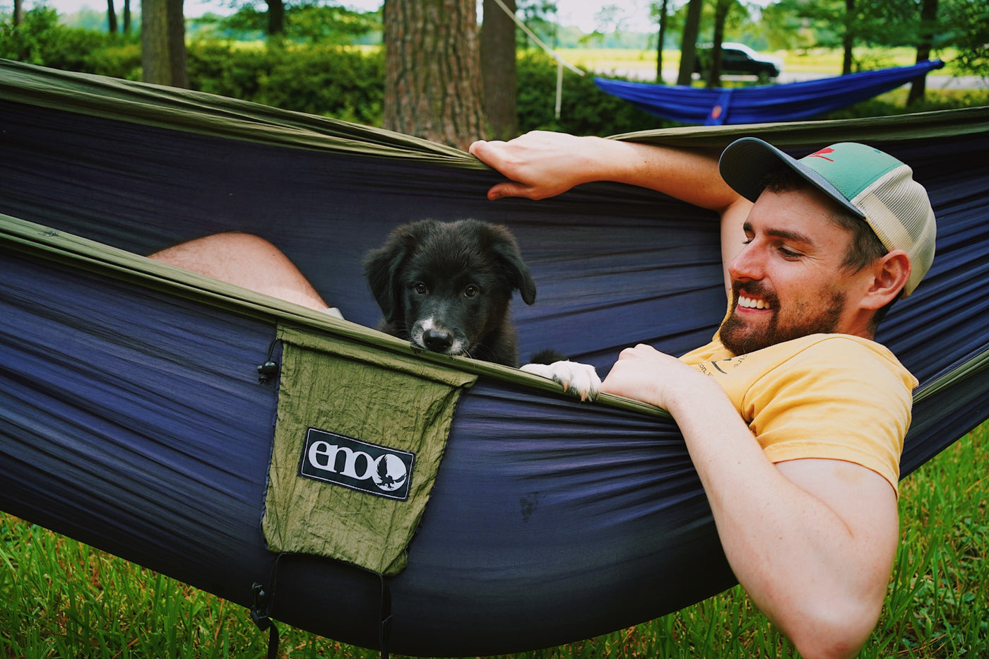 A man and his dog lay together in an ENO hammock. 