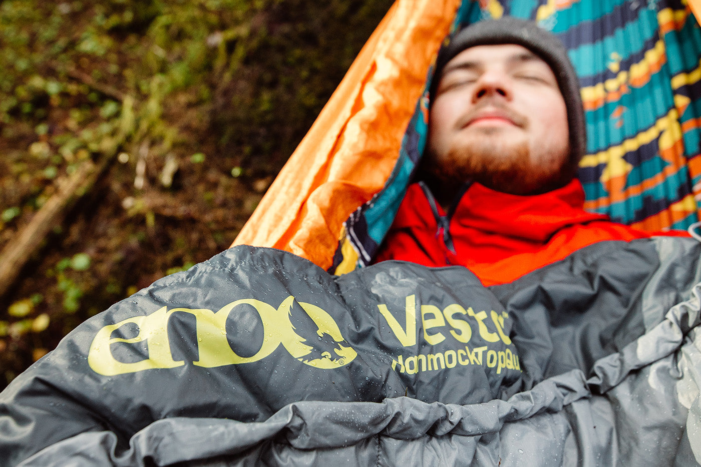 A man sleeps while using a Vesta TopQuilt in a hammock.