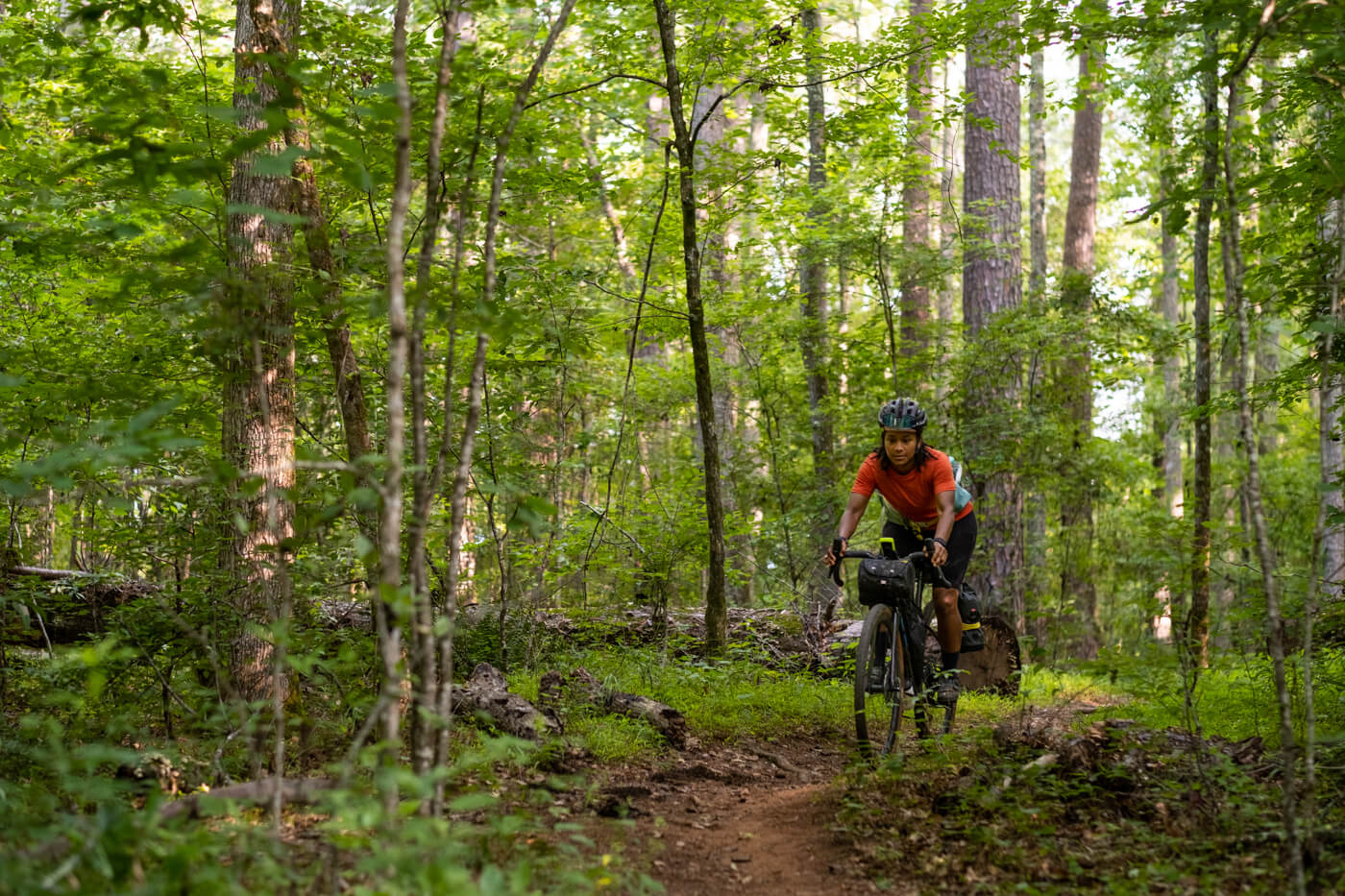 A woman rides her mountian bike through the forest.