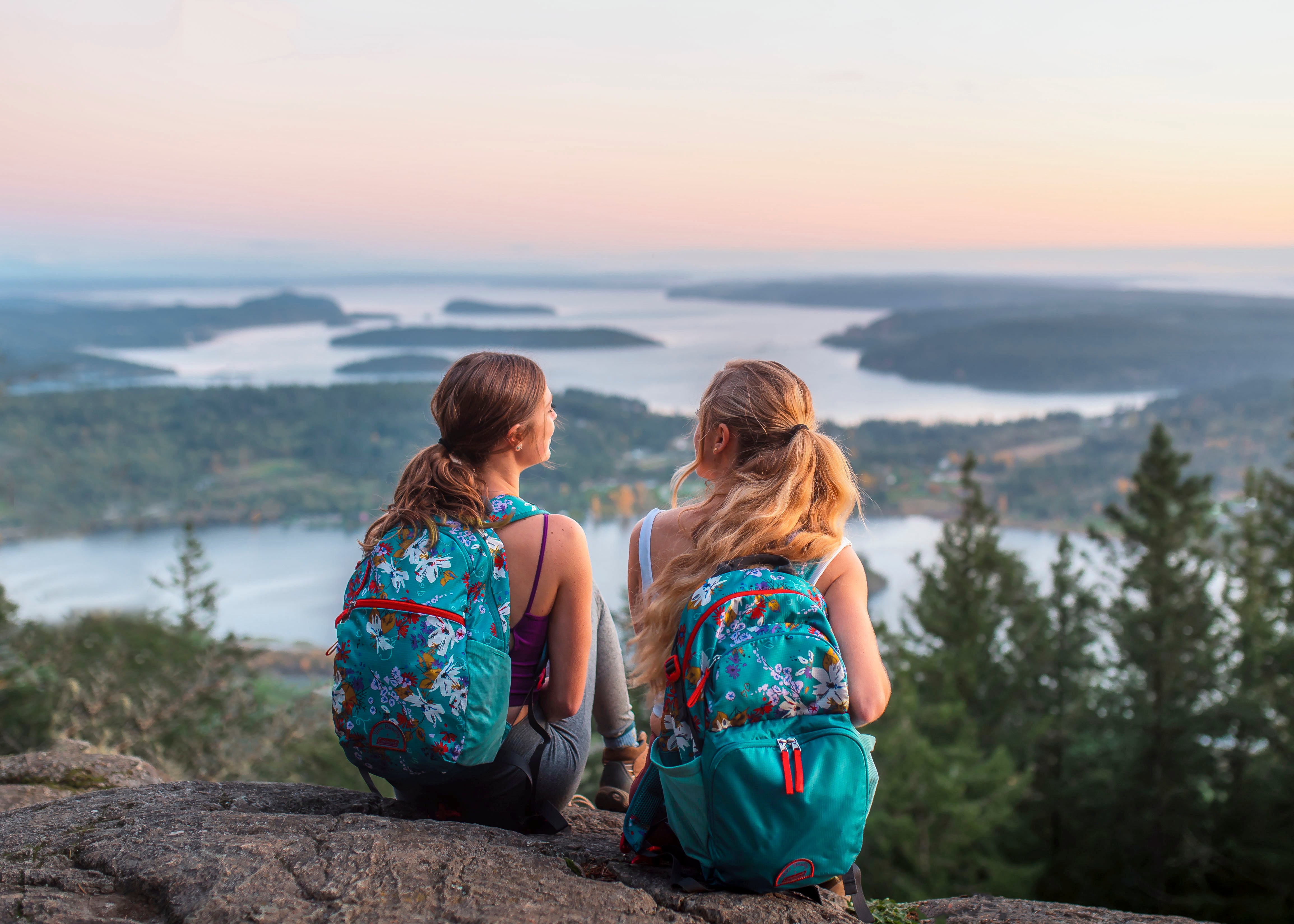 Two girls sitting with backpacks on