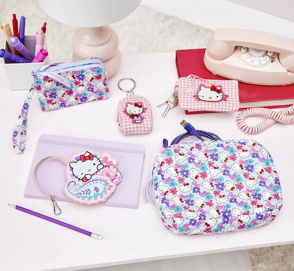 Hello Kitty wallets bag charms and other accessories on a desk with lamp and telephone