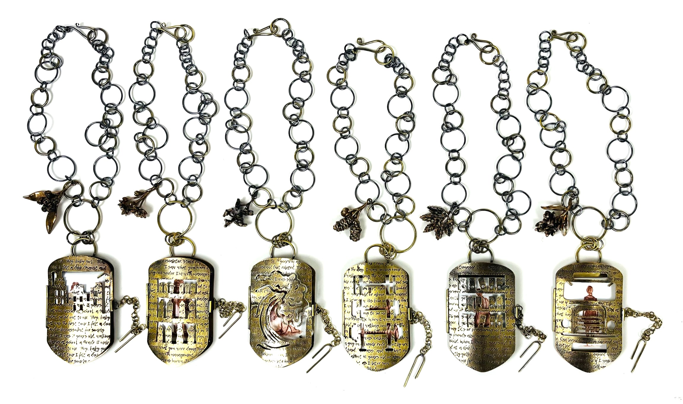 Six brass lockets with chains etched with the words of women who have experienced the male gaze.
