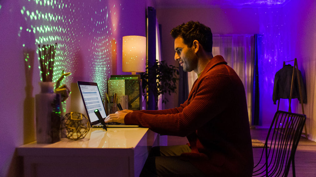 man using laptop with table lamp and starport usb lights in green