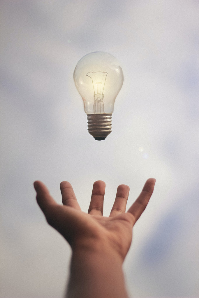 hand with levitating light bulb