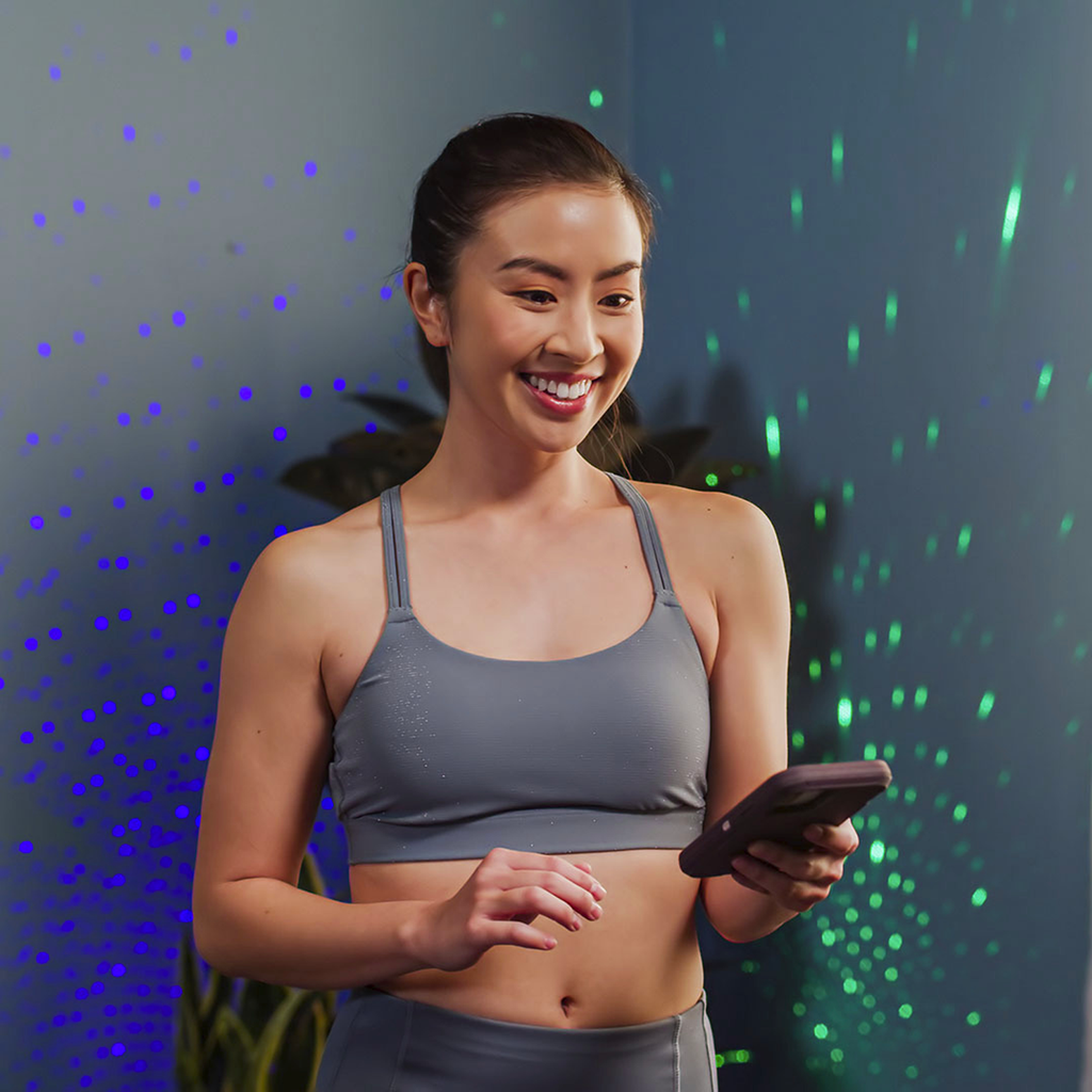 asian woman in workout clothes controlling lights with phone app