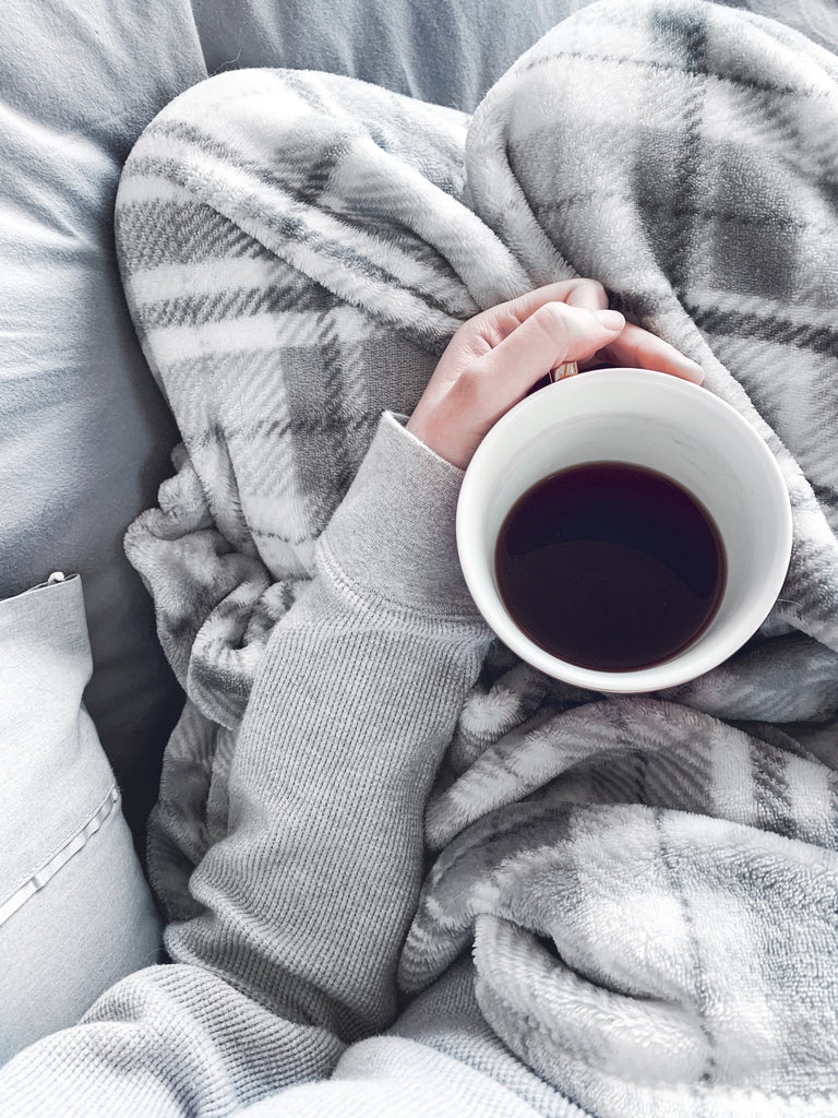 woman drinking tea with gray plaid blanket