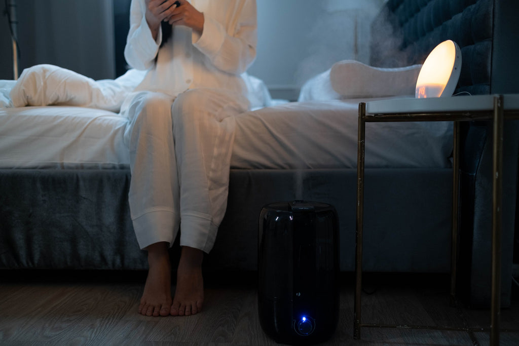 woman sitting in bed next to humidifier