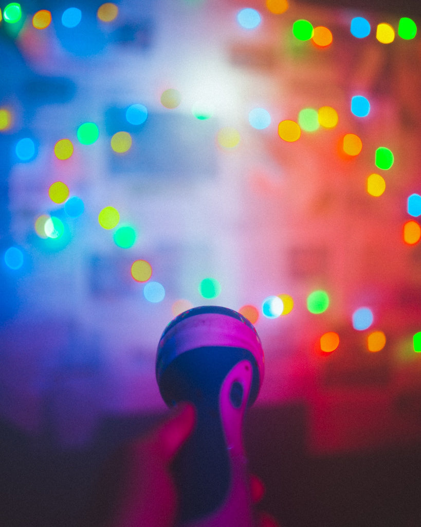 person holding flashlight in room with colorful string lights