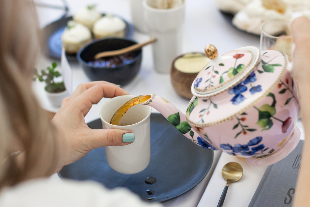 woman pouring tea from floral tea pot