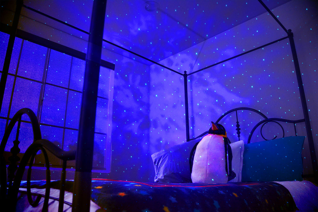 galaxy lights in bedroom with space throw blanket and stuffed penguin