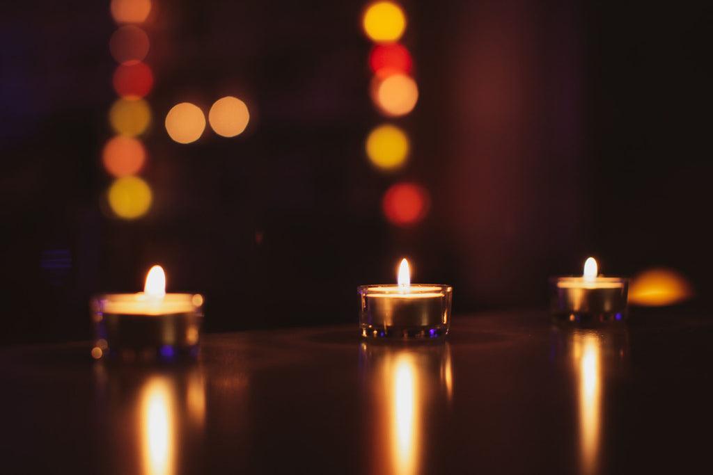 three tea lights on reflective table, warm lighting