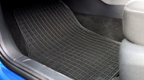 Black rubber car mat placed in the footwell of a car.