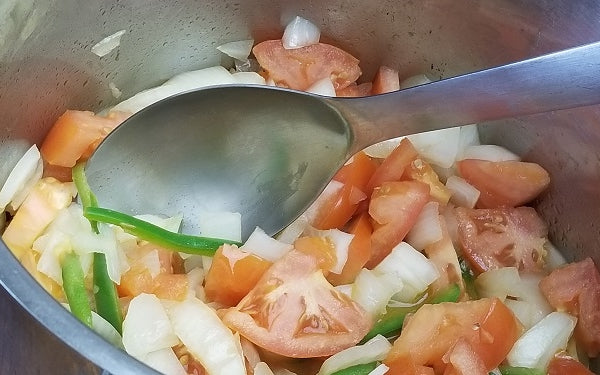 Heat oil in a large soup pot, then sauté onions, tomatoes, and pepper.