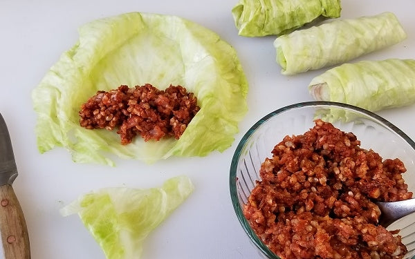 Working with one leaf at a time, place a leaf on a cutting board and slice out the thickest part of the spine (just a bit!) to make it more pliable to roll. Depending on the size of each leaf, place 1-2 heaping tablespoons of filling across the lower end and roll up, tucking ends in like a burrito.