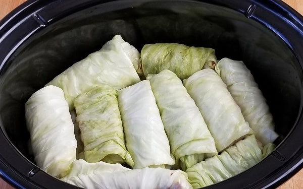 Build layers of flavor in the crockpot for the cook. The first layer consists of half of the onions and sauerkraut. Then place a single layer of all the cabbage rolls over this sauerkraut mixture.