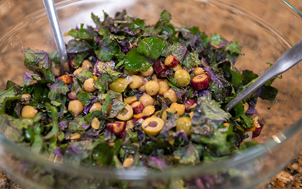 In a large bowl add the kale sprouts, garbanzo beans, watermelon radishes, carrots, and olives, and toss to combine. Add the beets and avocado on top. Sprinkle on the pepitas. Drizzle the dressing over the salad. Lightly toss to combine, and serve.
