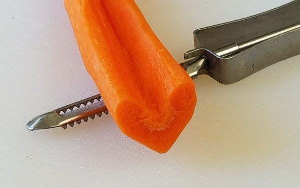 Using a potato peeler have your kitchen helpers peel the outer skin of each carrot. Then, with the same peeler, gently round off the pointed edges of both sides of the notch all the way down the carrot.