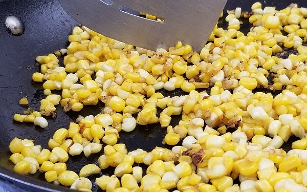 While the squash mixture is simmering, use the remaining oil to sauté the corn in a separate pan just long enough to give the kernels a slight browning. 
